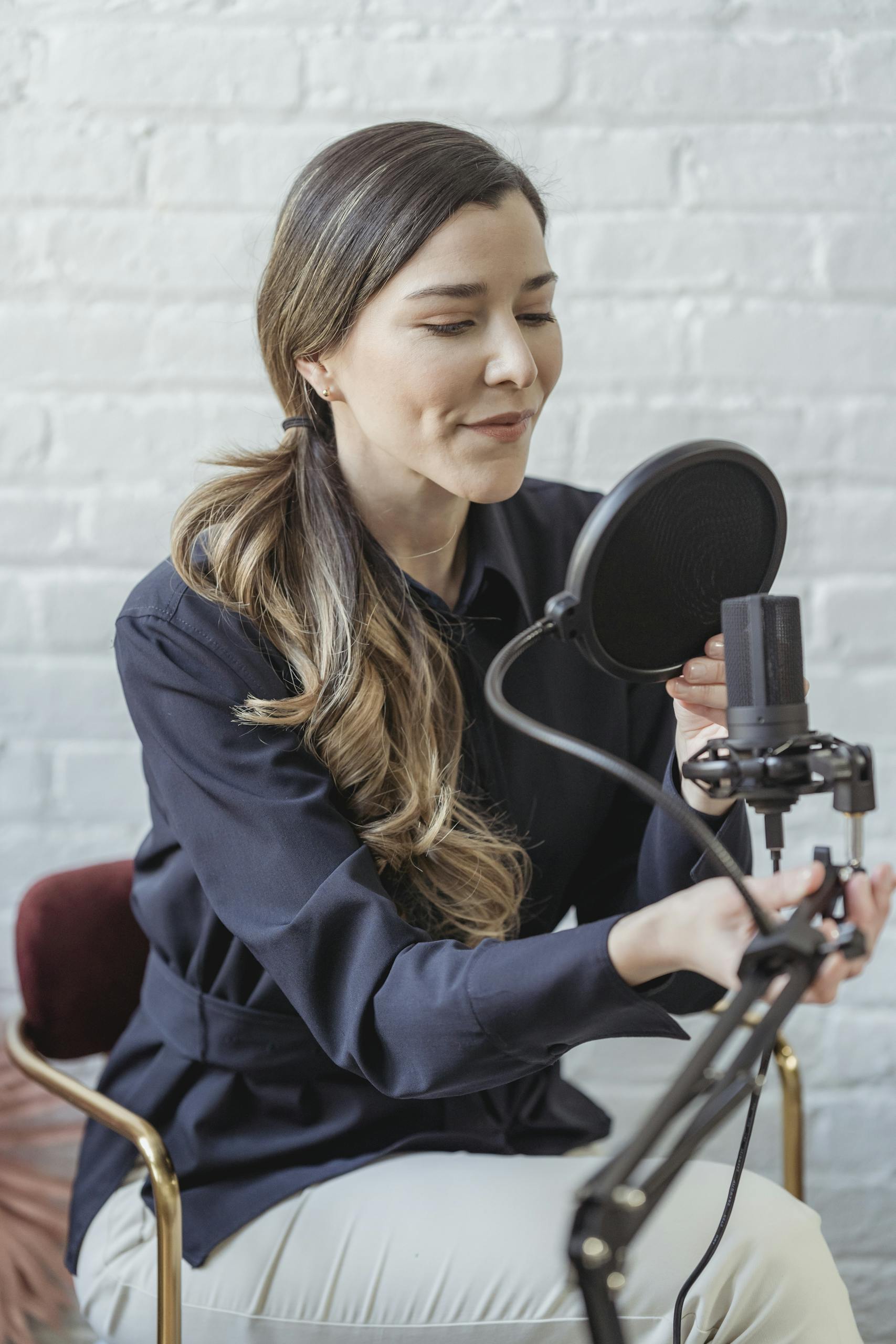 woman recording a podcast in a modern studio with a microphone and pop filter showcasing a professional setup. 6954171 scaled